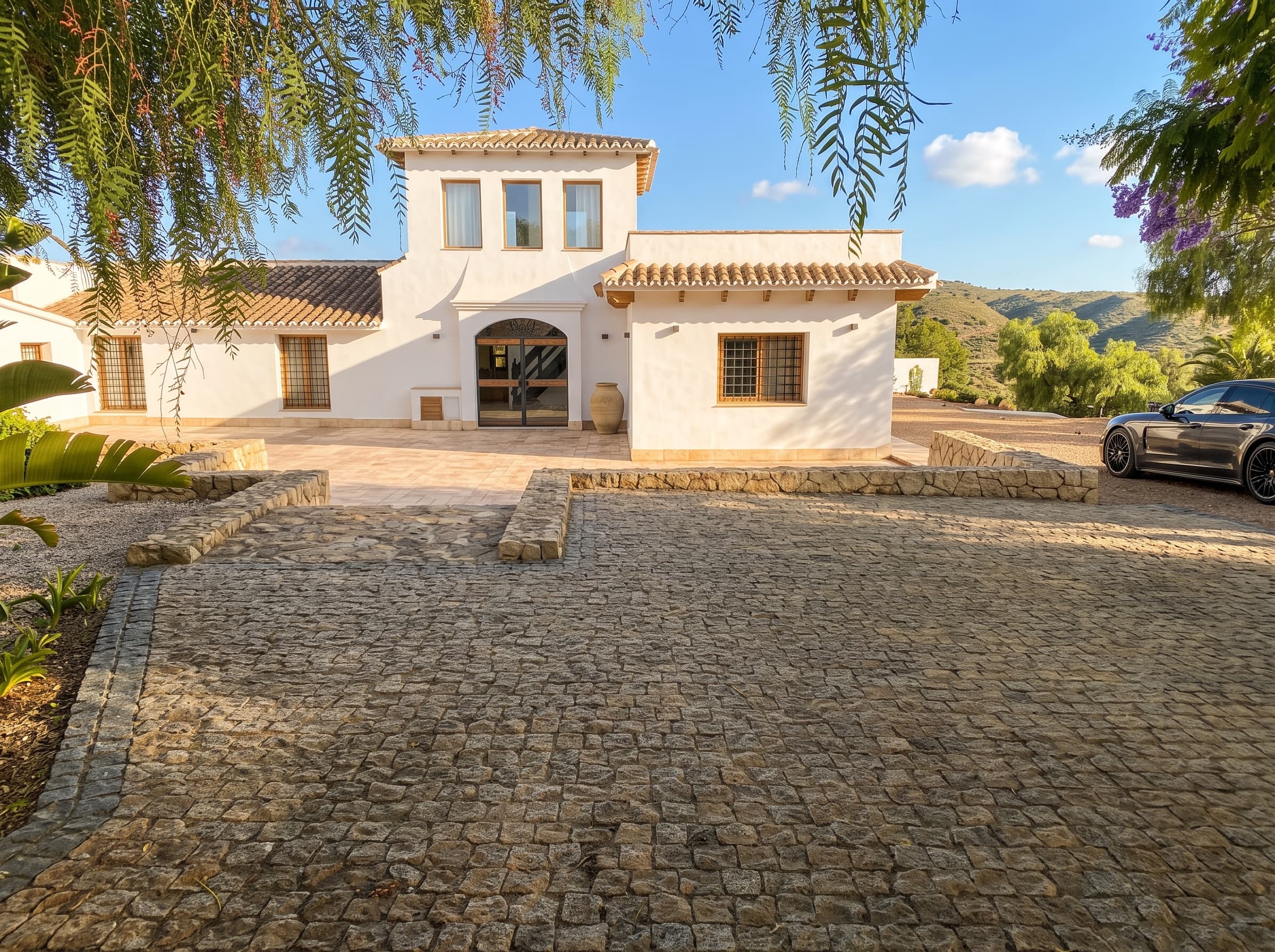Fachada principal del cortijo a pleno sol, con la sierra al fondo